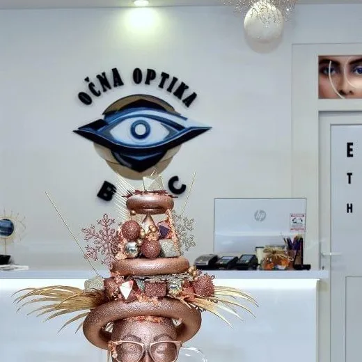 Logo optike na zidu iznad pulta s ukrasnom figurom